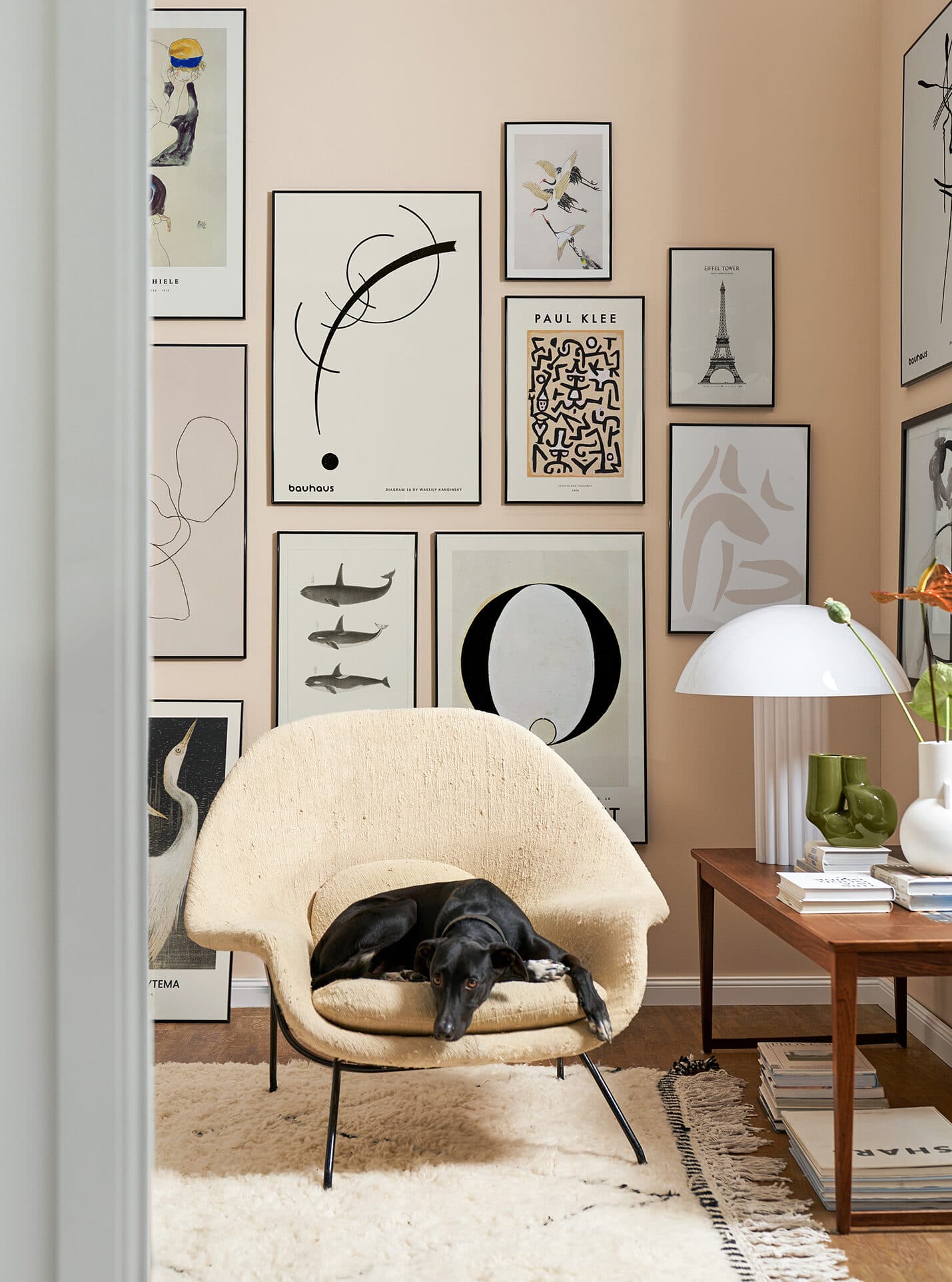 styling prop-styling set-design interior-styling peach coloured walls with Junique paintings, beige lounge chair wood side table white lamp books